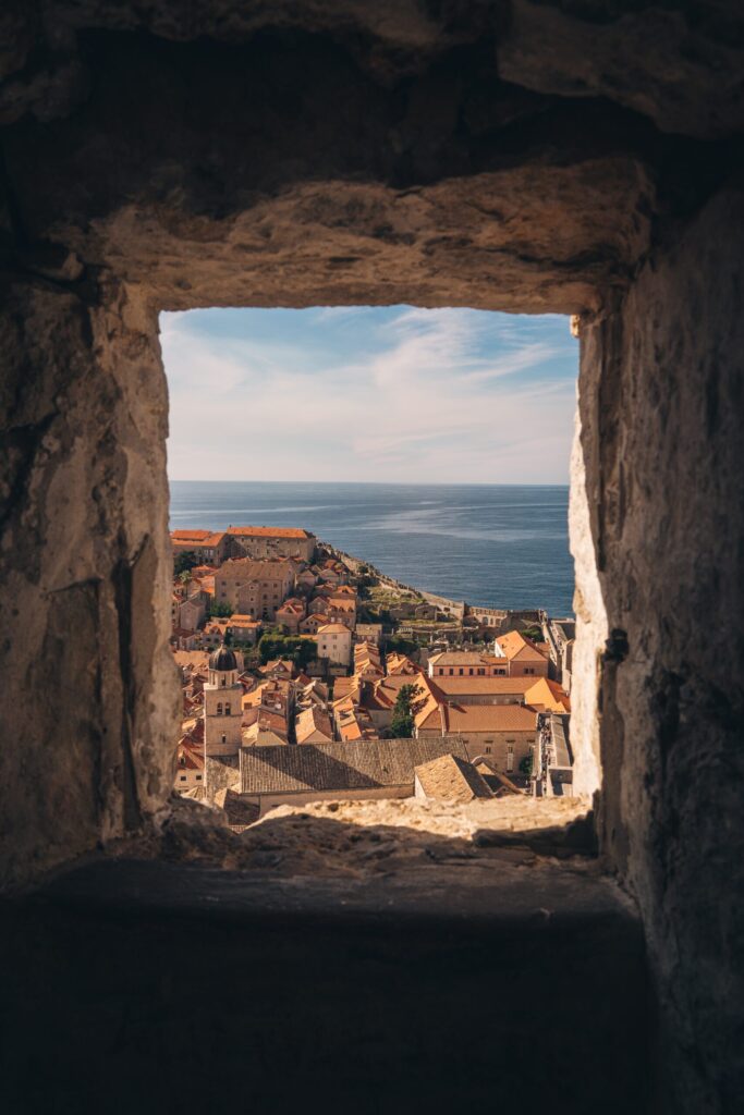 A wall opening with a view of a cityscape by the sea in the background in Croatia, Dubrovnik